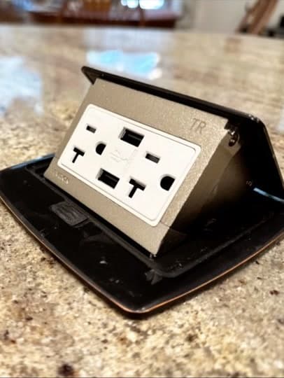 Pop-up outlet with USB charging set into a granite countertop