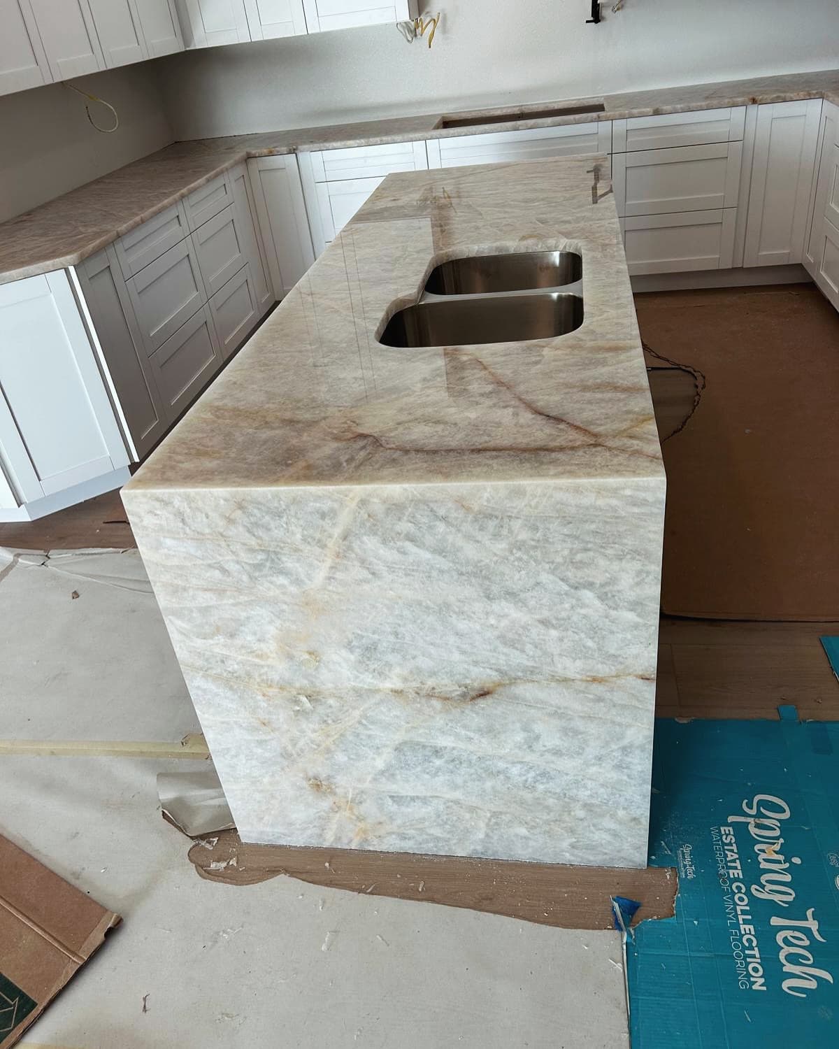 Taj Mahal quartzite island with waterfall edges over dark cabinets