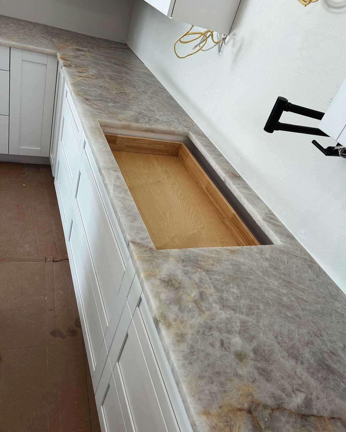 Quartzite countertop with a cooktop cutout, pot filler on the wall above