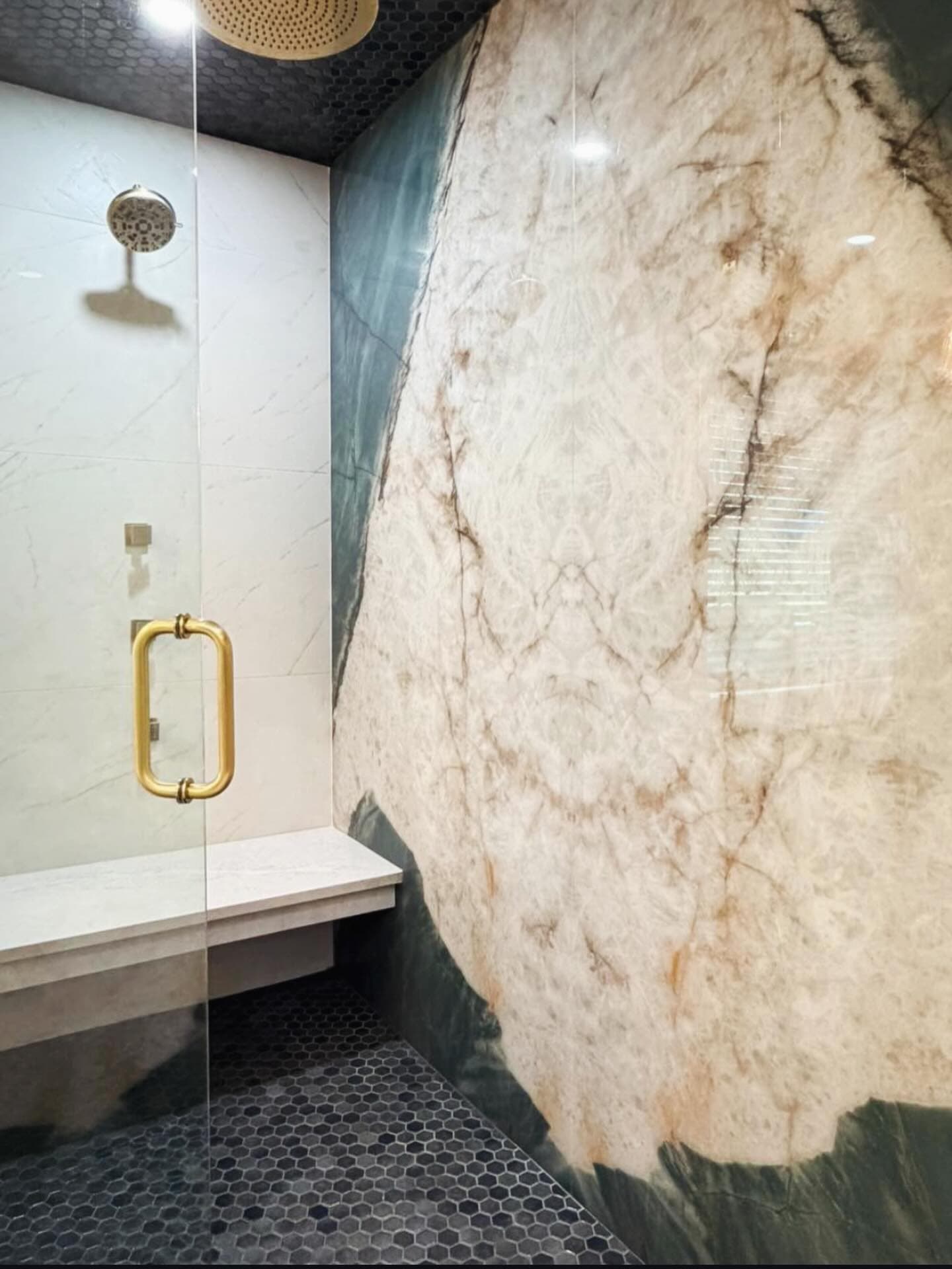 Book-matched gold-veined quartzite shower wall with brass hardware