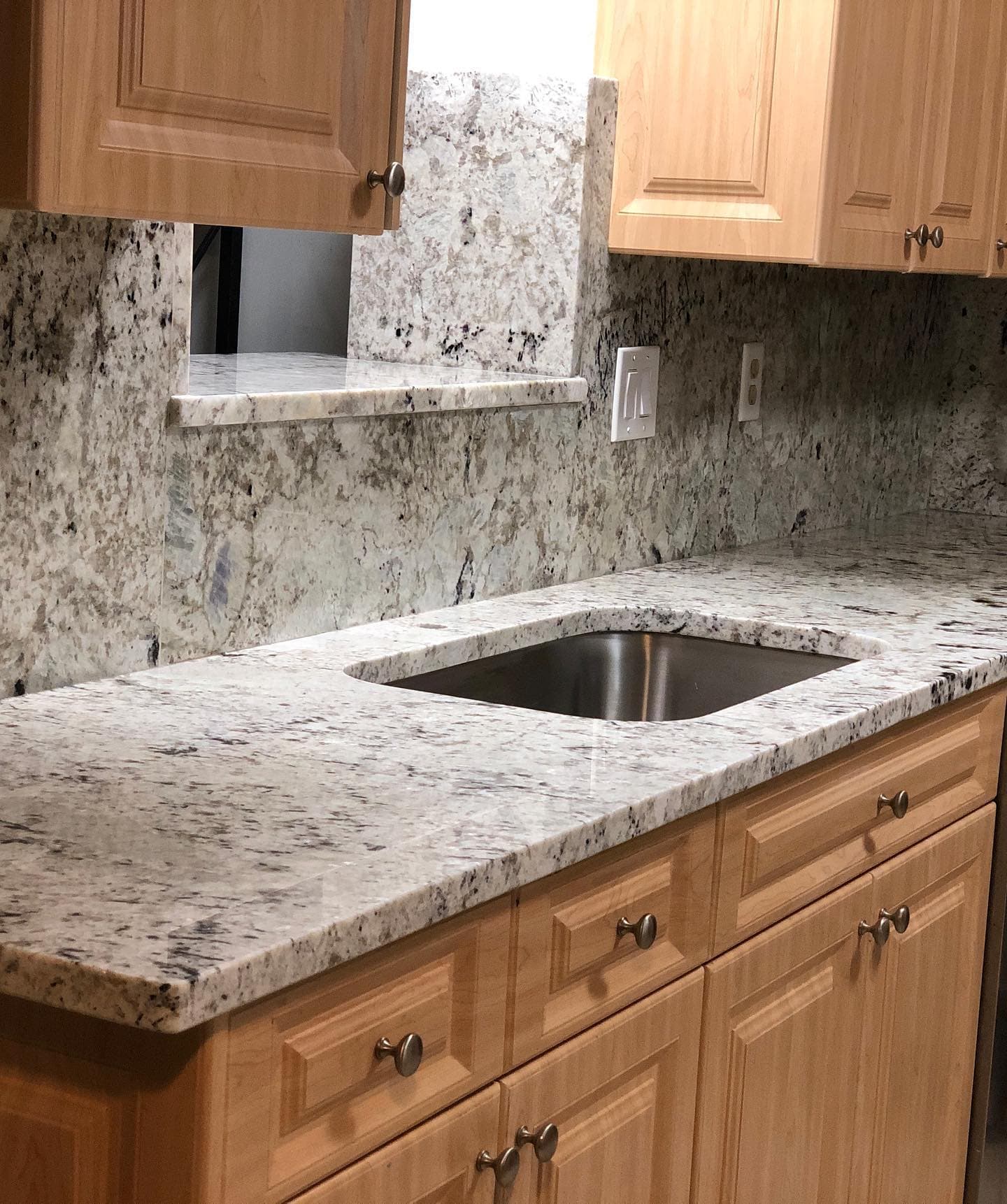 White granite countertop with full-height granite backsplash